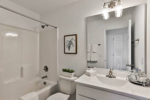 A white bathroom with a towel on the toilet.