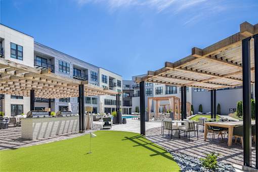 A modern building with a patio area and a green lawn at Plaza at Pinnacle Hills, Rogers, AR, 72758