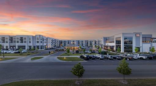 A parking lot with cars and a building in the background during sunset.