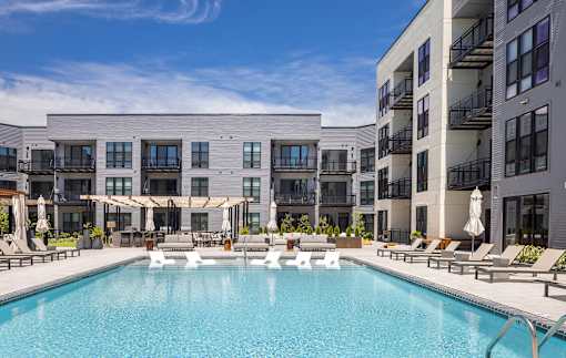 A large swimming pool in front of a modern apartment building.