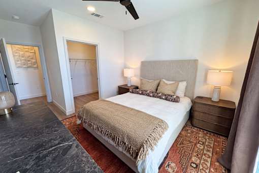 A bedroom with a large bed and a rug on the floor.