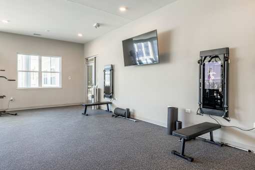 A spacious room with a bench, television, and exercise equipment.at Preserve at Sycamore Creek, Missouri 65065
