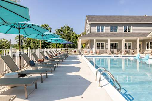 A pool area with sun loungers and umbrellas.at Preserve at Sycamore Creek, Missouri 65065
