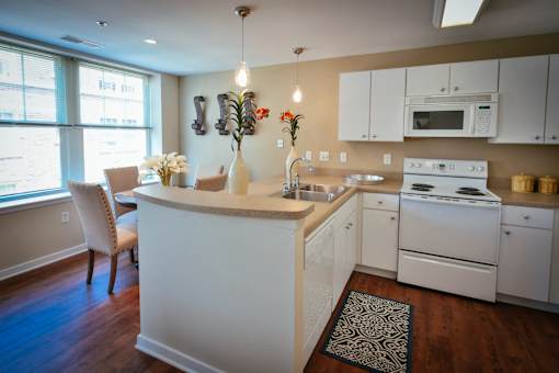 L-shaped kitchen with white cabinets and white range at Residences at Forest Park, Saint Louis, MO, 63108