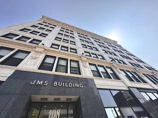The JMS Building is a tall, gray structure with many windows.