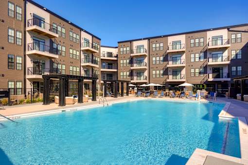 A large swimming pool is surrounded by apartment buildings. at The Cunningham Apartments, West Des Moines, IA, 50266