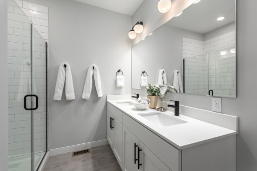 a white bathroom with a sink and a shower at The Flats & Terraces at Wildhorse Village, Missouri