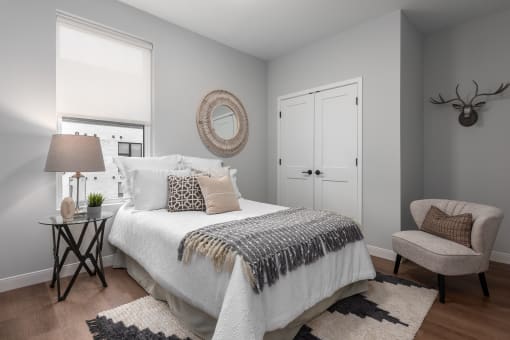 a bedroom with a bed and a chair and a mirror at The Flats & Terraces at Wildhorse Village, Missouri
