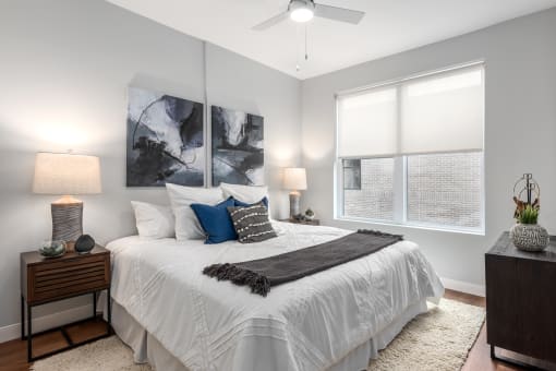 an empty bedroom with a white bed and a ceiling fan at The Flats & Terraces at Wildhorse Village, Chesterfield