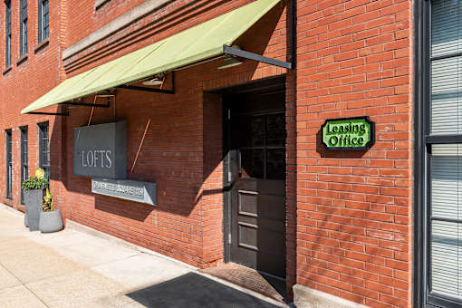 a brick building with a green awning and a door to a tasting room at Lofts at Lafayette Square Apartments, Missouri