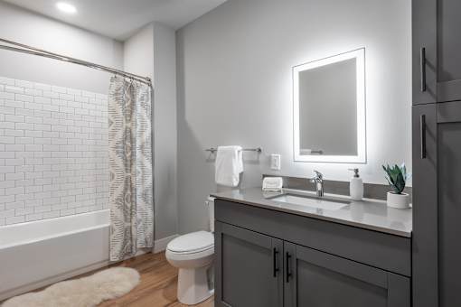 A modern bathroom with a white toilet, a sink with a mirror, and a shower with a glass door.