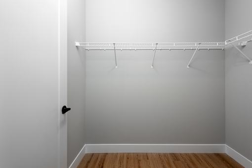 A white closet with a shelf and a black door handle.