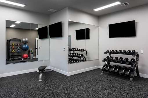 A gym room with a mirror, weights, and exercise equipment.