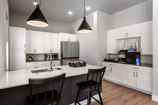 A modern kitchen with a white countertop and black chairs.