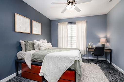 A bedroom with a bed, desk, and chair.