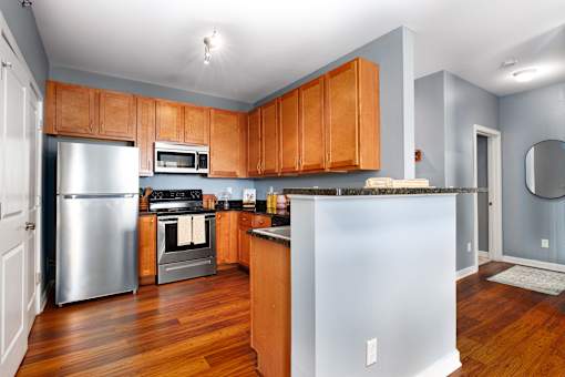 A kitchen with wooden cabinets and a stainless steel refrigerator.