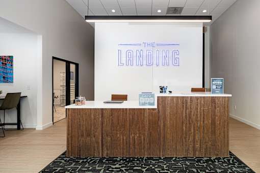A reception area with a brown wood desk and a sign that says "The Landing".
