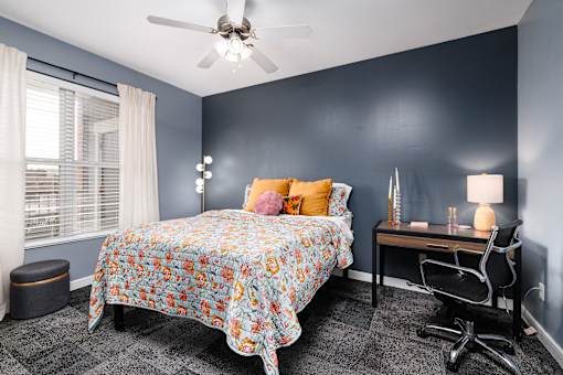 A bedroom with a bed, desk, and chair.