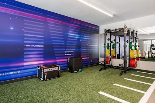 A gym with a green carpet and a purple wall with the words "work and determination" written on it.