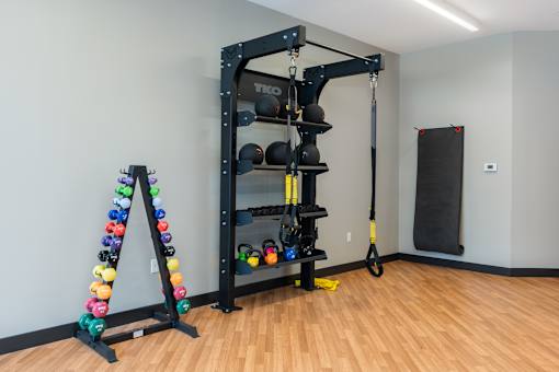 A gym with a weight rack and a set of dumbbells.