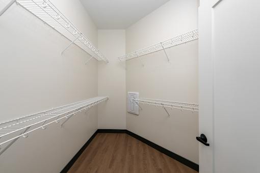 A white closet with a door on the right and a white wall on the left.
