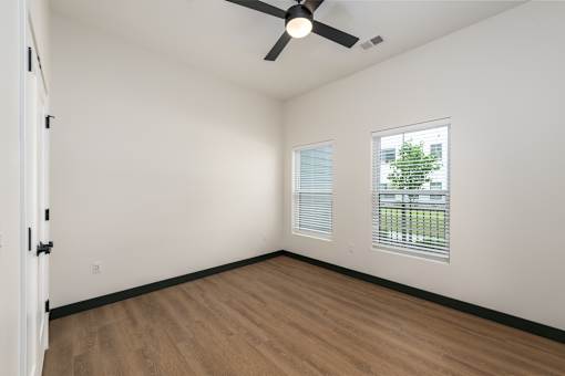 A room with a ceiling fan and a window with blinds.