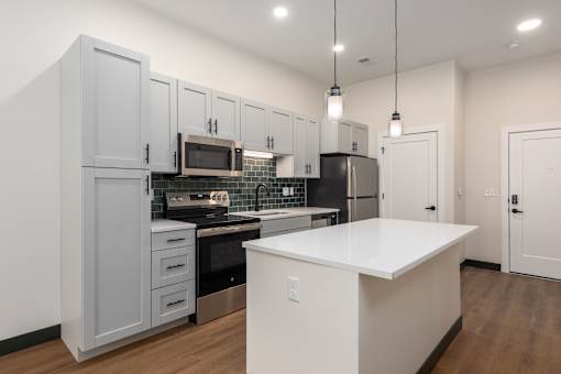 A kitchen with a white countertop and grey cabinets.