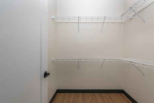 A white closet with a door and shelves.