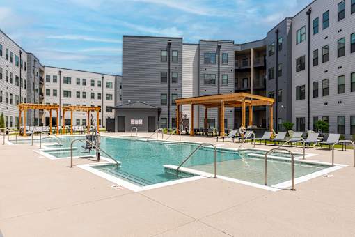 A swimming pool area with a wooden pavilion and lounge chairs.