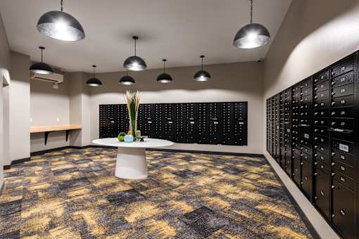 A room with a patterned carpet and a vase of flowers on a pedestal.