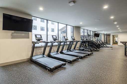 A gym with treadmills and a television on the wall.