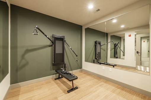 A gym room with a mirror, a bench and a weight machine.