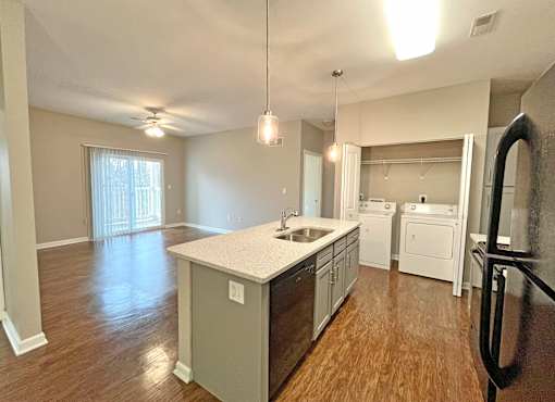 A kitchen with a white countertop and wooden floors.