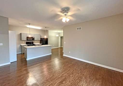 A spacious living room with a white ceiling fan and wooden flooring.