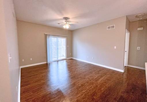 A room with wooden flooring and a ceiling fan.