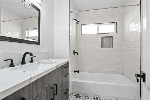 a white bathroom with a tub and a sink and a mirror