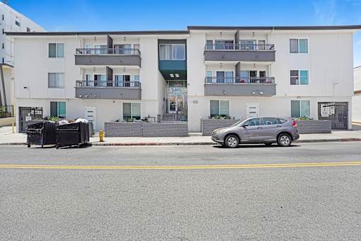 A car is parked on the side of a street in front of a building.