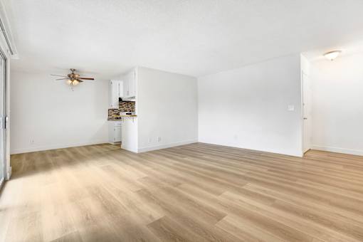 A room with a ceiling fan and wooden flooring.