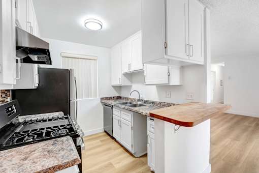 A kitchen with a black stove top oven and white cabinets.