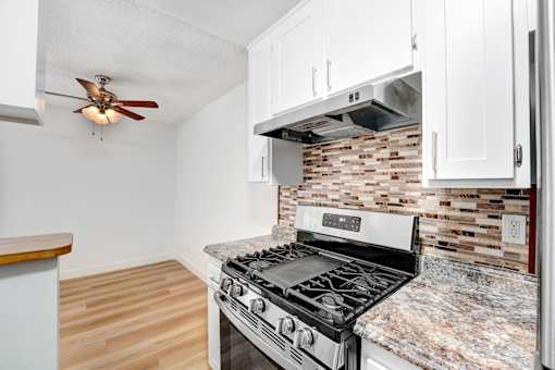 A kitchen with a stove and a fan on the ceiling.