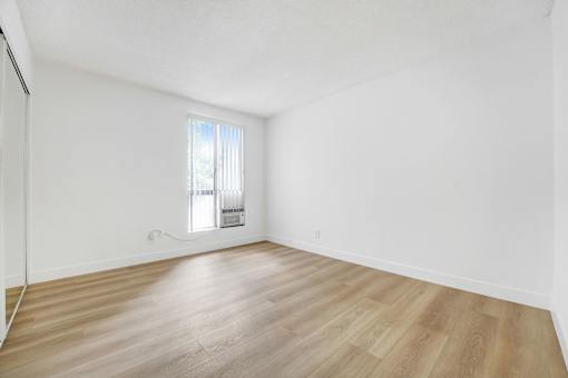 A room with wooden flooring and a window with blinds.