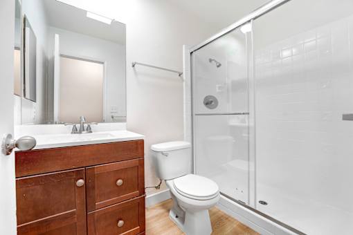 A white toilet sits in a bathroom next to a sink and a shower.