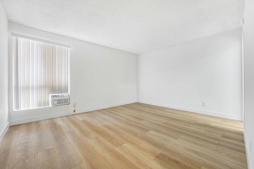 A room with wooden flooring and a window with blinds.