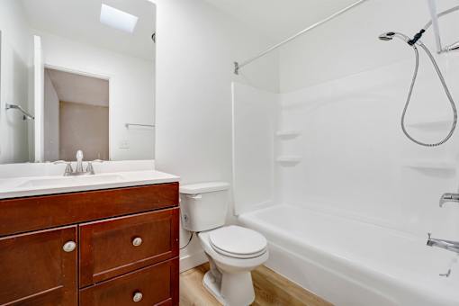 A white bathroom with a wooden vanity and a white toilet.