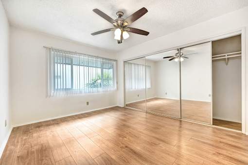 A room with a ceiling fan and sliding glass doors.