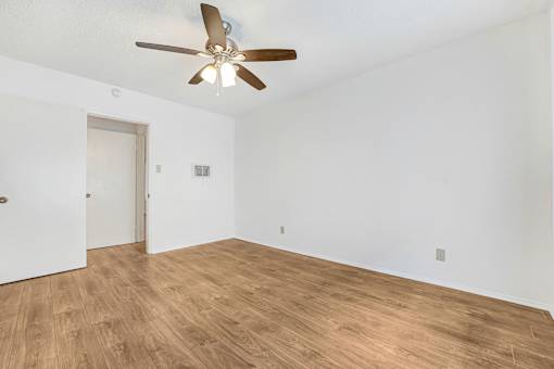A room with a ceiling fan and wooden flooring.