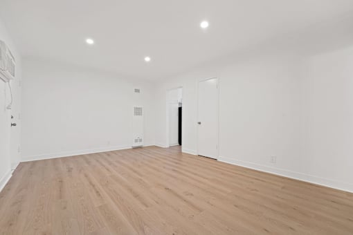 A room with wooden flooring and white walls.