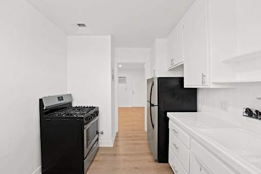 A black stove and refrigerator in a white kitchen.