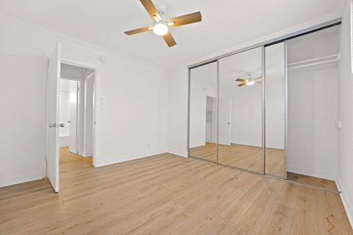 A room with a ceiling fan and mirrored doors.