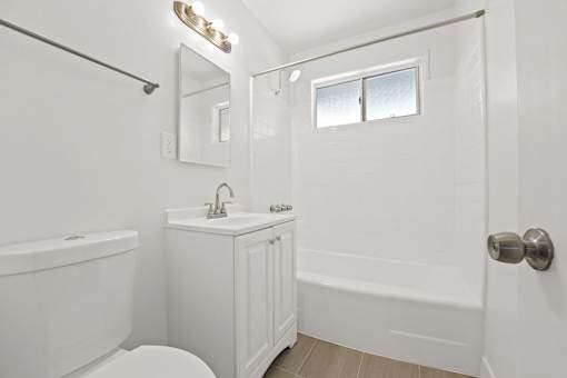 A white bathroom with a toilet, sink, and bathtub.